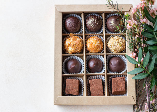 istock Gift craft box with assorted chocolates and pink flowers on a light concrete background. Top view. 1310096063