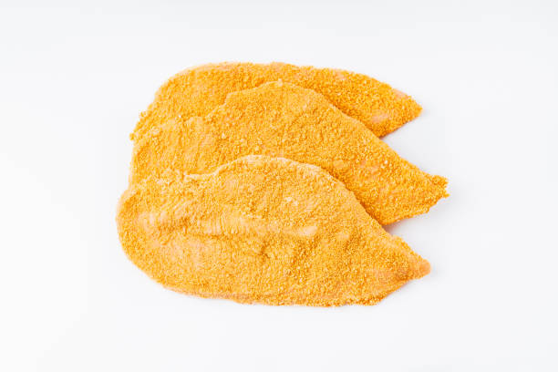 raw chicken fillet sprinkled in a bright breading.three slices of breaded schnitzel, sliced on a white background. - schnitzel cutlet food meal imagens e fotografias de stock