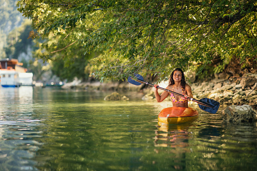Adult female paddling a kayak on a river during sunny day