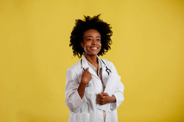 istock Young afro-american doctor is posing against yellow background. 1310097236
