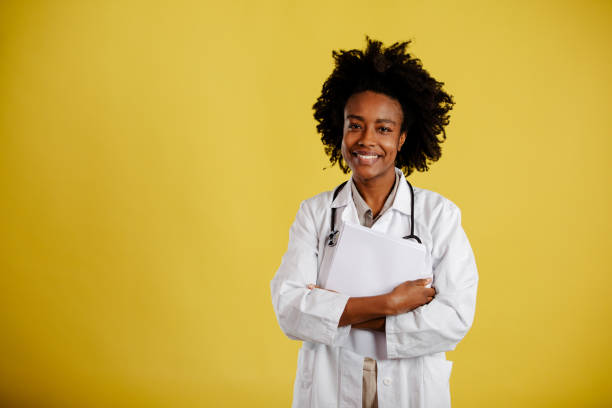 istock Young afro-american doctor is posing against yellow background. 1310097239