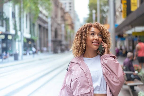 istock Woman talking on mobile phone while walking along downtown city street 1310097559