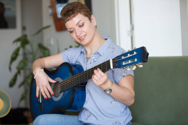 istock pretty woman learning to play guitar at home 1310098346