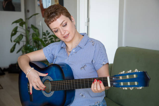 istock pretty woman learning to play guitar at home 1310098356