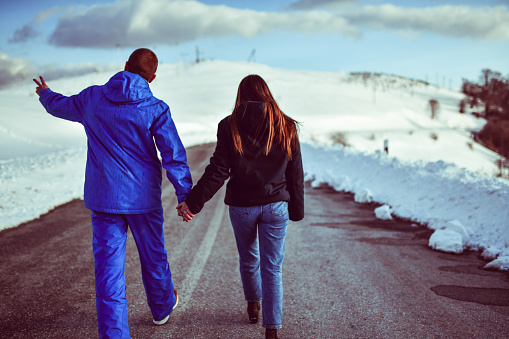 Couple Waking Down Snowy Road While Holding Hands