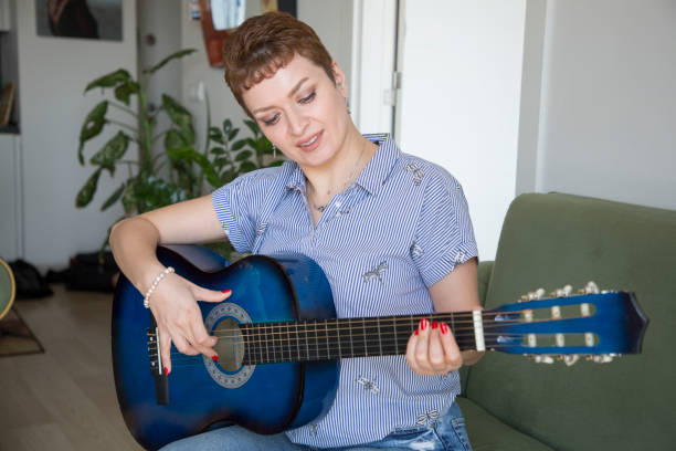 istock pretty woman learning to play guitar at home 1310098379