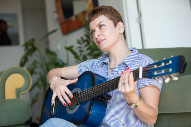 istock pretty woman learning to play guitar at home 1310098429