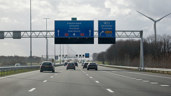 Deventer, Overijssel, Netherlands, march 27th 2021, rear view of daytime traffic on Dutch highway A1 at exit 23 towards Deventer and Zutphen  - the motorway crosses 4 provinces: North Holland, Utrecht, Gelderland and Overijssel from Amsterdam to the German border, 157 kilometers in total