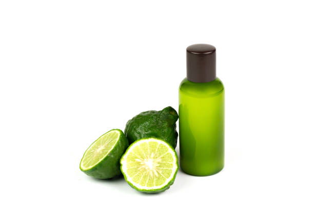 Shampoo made of bergamot in green plastic bottle and fresh bergamot fruit and sliced isolated on white background. Natural products used to care for hair and scalp concept.