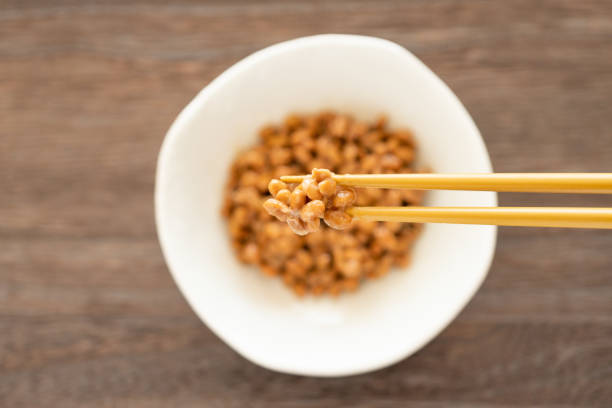 het opheffen van natto met eetstokjes (japans voedsel) - natto stockfoto's en -beelden