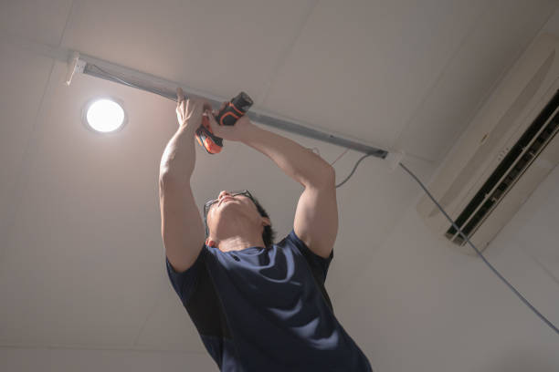istock Asian Chinese electrician man installing electric lamp on ceiling using cordless drill. 1310102454