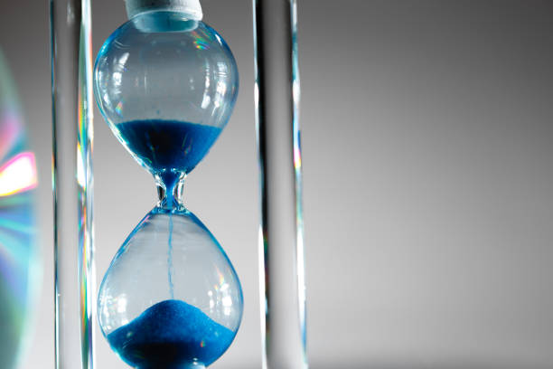 istock Blue hourglass on gray background close up 1310103017