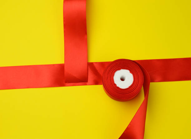istock red wide silk ribbon on yellow background 1310103202