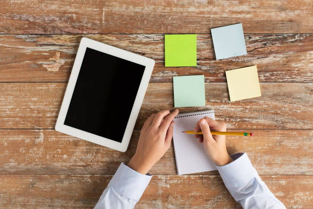 istock close up of hands with tablet pc and notebook 1310103592