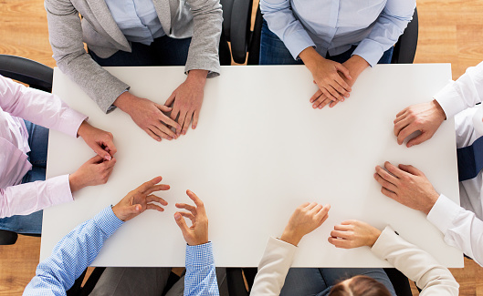 business, people and team work concept - close up of creative team sitting at table in office