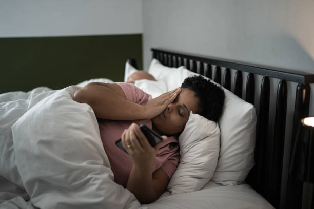 mujer en la cama revisando teléfono inteligente - sleeping insomnia alarm clock clock fotografías e imágenes de stock