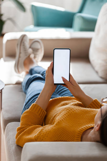 istock Young woman hold mobile phone in hands, lying on the sofa 1310106246