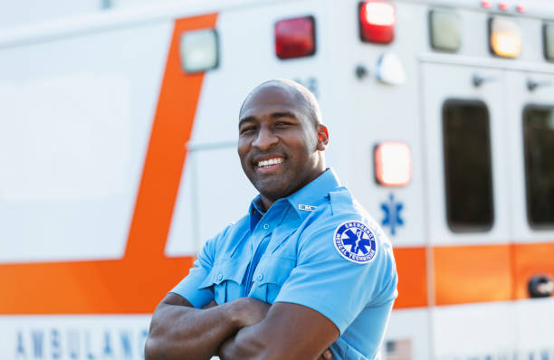 Paramedic in front of ambulance A paramedic standing in front of an ambulance, looking at the camera. He is an African-American man in his 30s. emt stock pictures, royalty-free photos & images