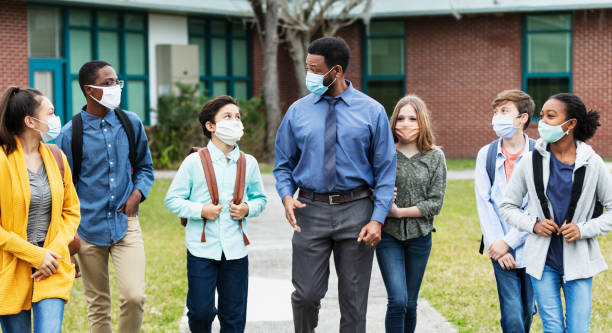 istock Teacher, middle school students walking outside building 1310106367