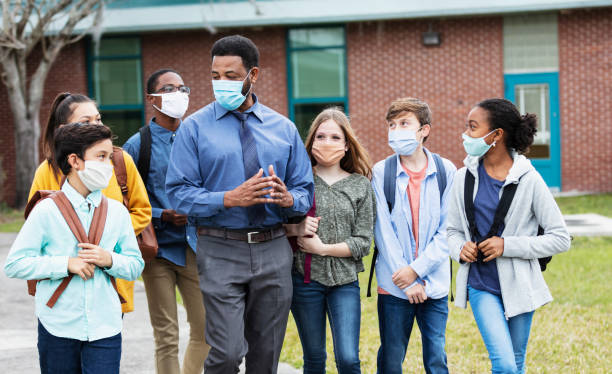 istock Teacher, middle school students walking outside building 1310106400