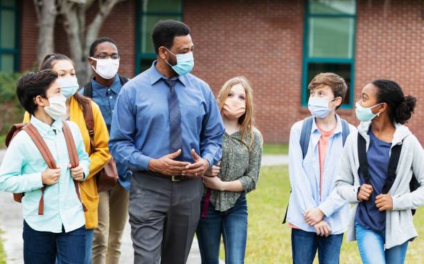 istock Teacher, middle school students walking outside building 1310106420