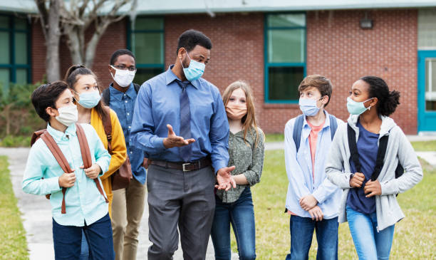 istock Teacher, middle school students walking outside building 1310106437