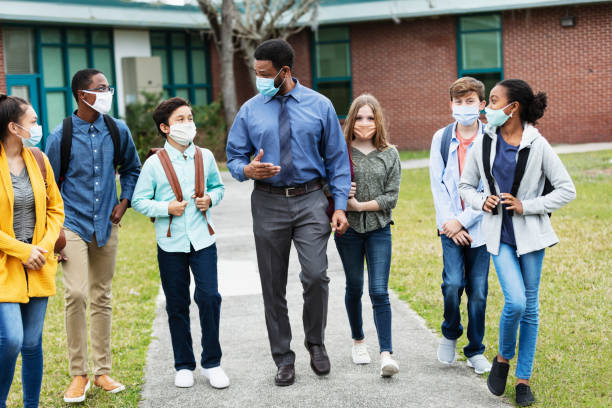 istock Teacher, middle school students walking outside building 1310106449