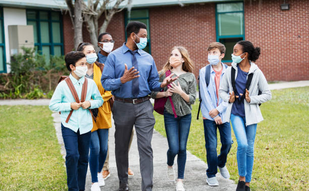 istock Teacher, middle school students walking outside building 1310106450