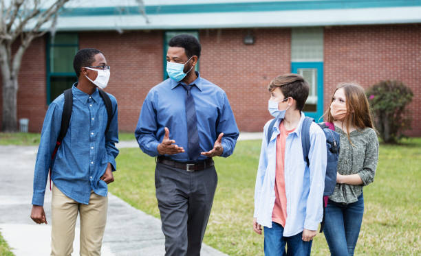 istock Teacher, middle school students walking outside building 1310106476