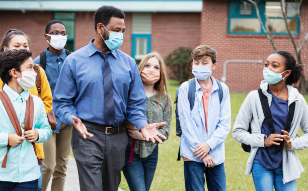 istock Teacher, middle school students walking outside building 1310106509