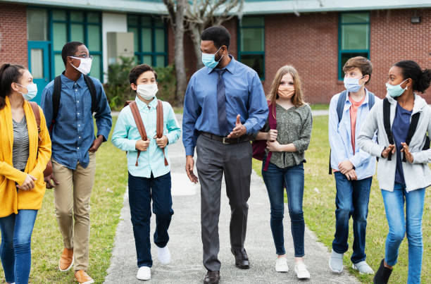 Teacher, middle school students walking outside building