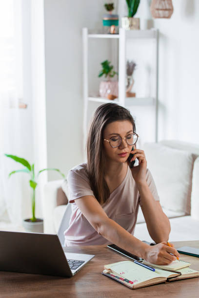 istock Young woman using mobile phone and laptop to work home, remote work 1310107244