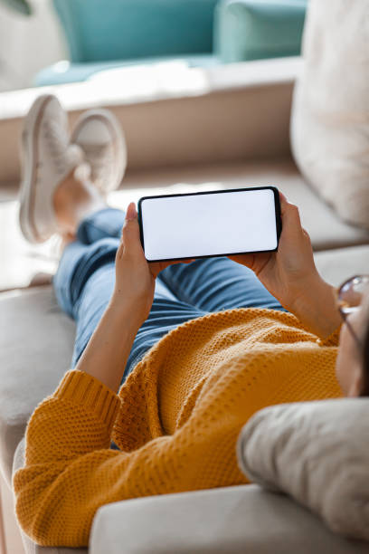 istock Young woman hold mobile phone in hands, lying on the sofa 1310107251