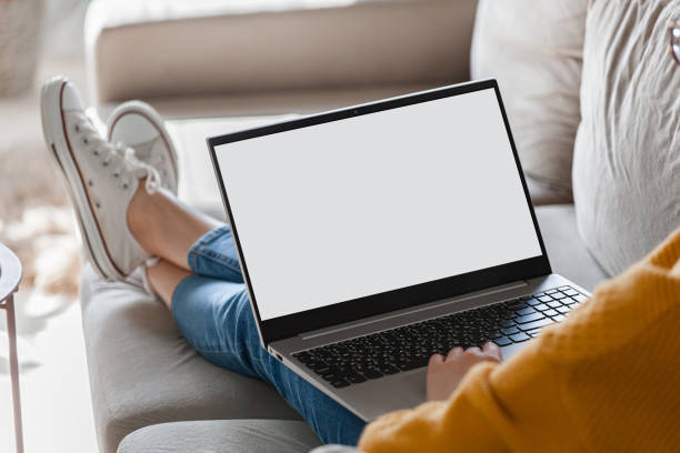 istock Young woman using laptop screen blank, mock up lying on sofa at home 1310107368