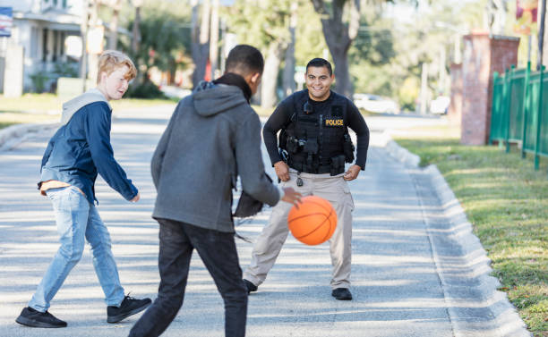 agente di polizia che gioca a basket con due giovani - basketball child dribbling basketball player foto e immagini stock