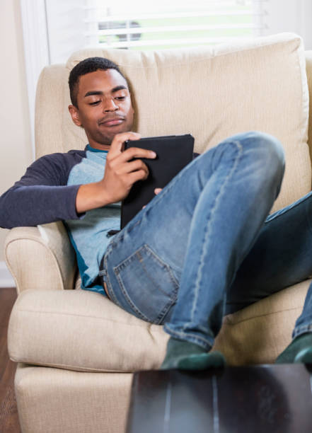 istock Young African-American man on armchair with tablet 1310109336