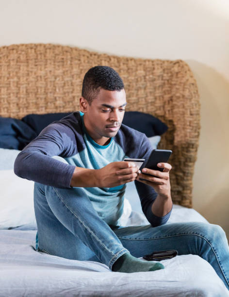 istock Young man shopping online from bed, holding credit card 1310109496