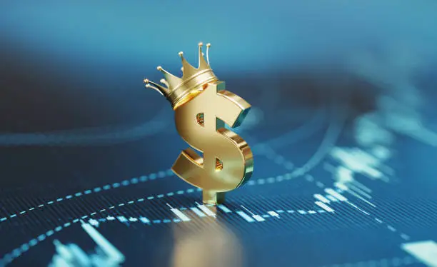 American dollar sign wearing gold crown sitting over blue financial chart. Horizontal composition with selective focus and copy space. Finance and stock market concept.