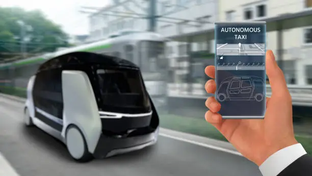 Control of autonomous taxi by mobile app.  Hand with futuristic phone on a background of self driving shuttle