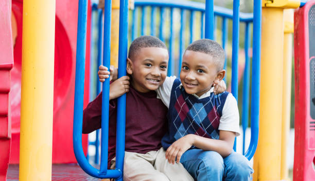 istock Twin brothers sitting together on playground 1310112790