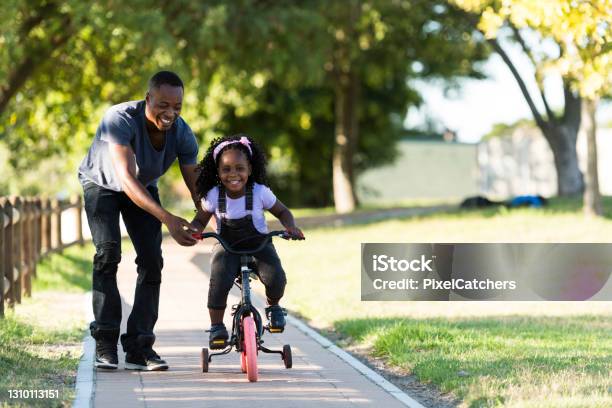 Front View Father Helps Excited Little Girl Riding Tricycle Stock Photo - Download Image Now