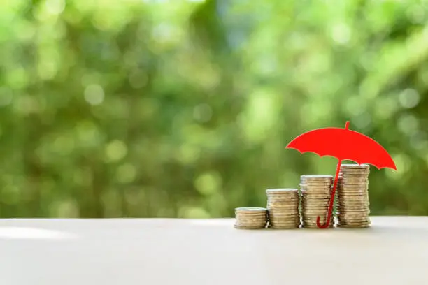 Photo of Red umbrella protects coins or cash on a table