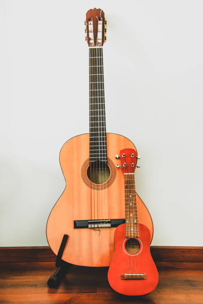 istock Classic six-string wooden guitar and Hawaiian four-string guitar Ukulele stand against the wall 1310118214