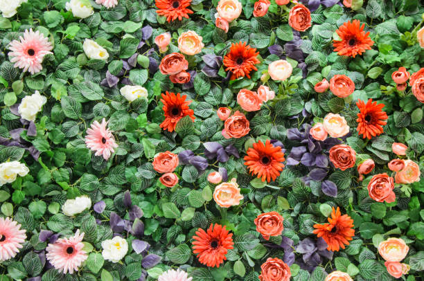 Background from artificial colorful flowers and leaves. Decorative wall made of artificial plants