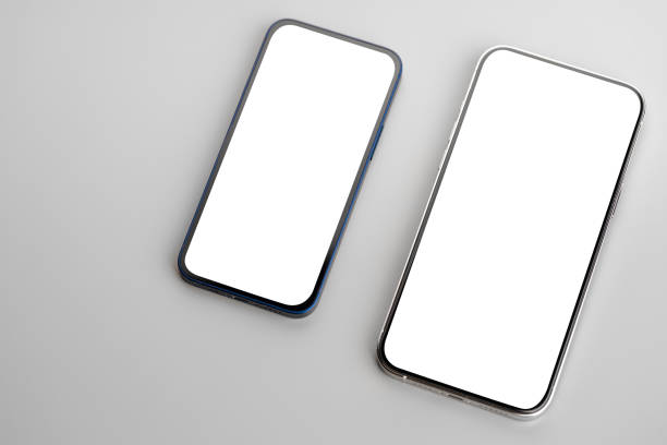 istock Two smartphones with blank white screen on gray background 1310119636