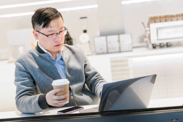 young man at coffee shop working on laptop