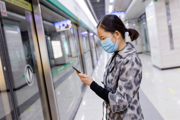 istock Asian woman with protective face mask using smartphone in the subway station 1310123281