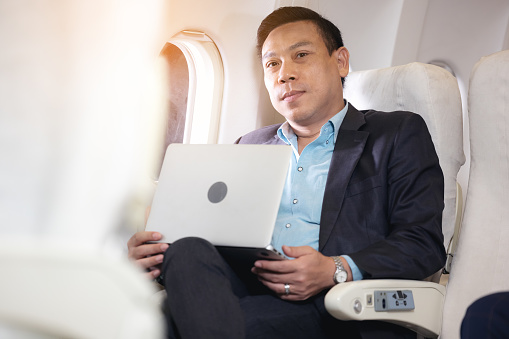 businessman with notebook sitting inside an airplane
