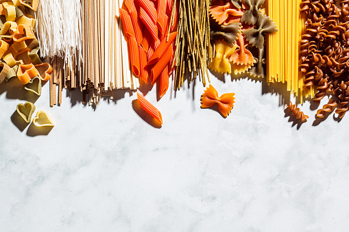 Different types of healthy pasta background. Raw noodles and spaghetti from rice, edamame, lentils, buckwheat and quinoa, top view.