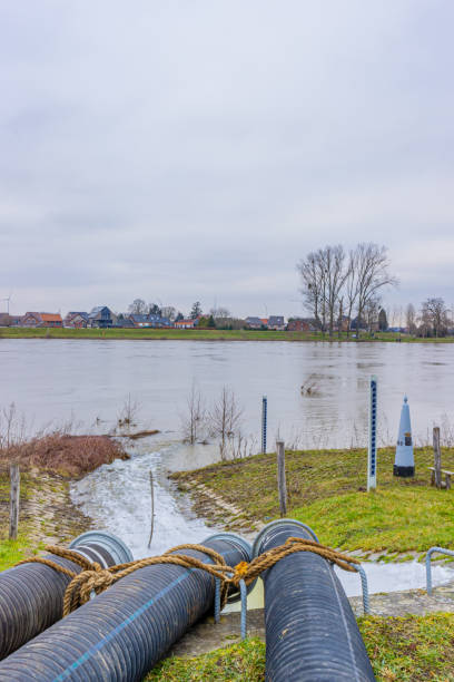 istock Three pipes of a water pump with water flowing into the Meuse river, system to control high levels of streams 1310125200